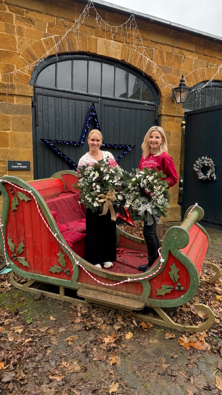 Holding Christmas Wreaths by a sledge outside at Delapre Abbey