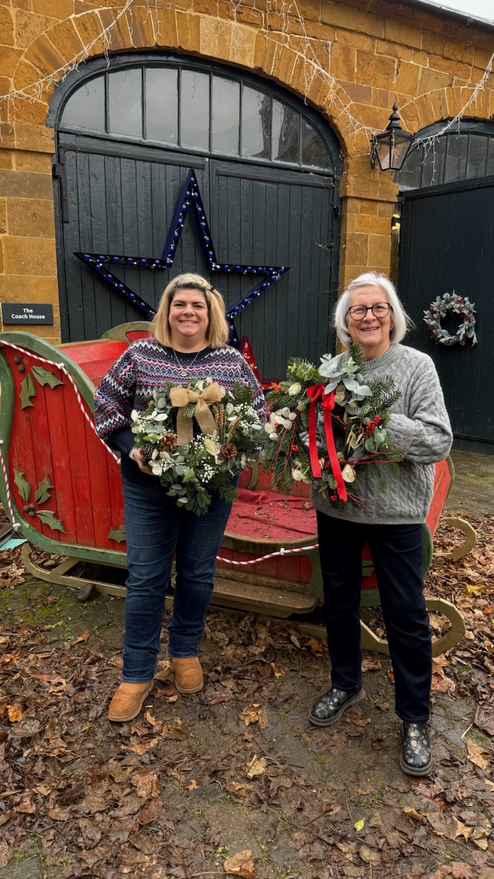 Two students showing their Christmas Wreaths after their florry Wreath Making