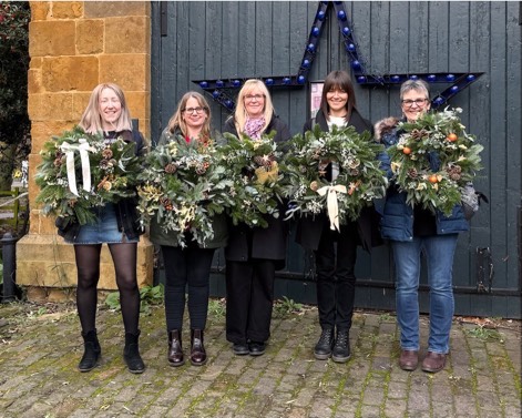Holding Christmas Wreaths by a sledge outside at Delapre Abbey