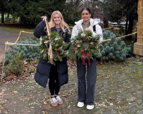 Two students showing their Christmas Wreaths after their florry Wreath Making