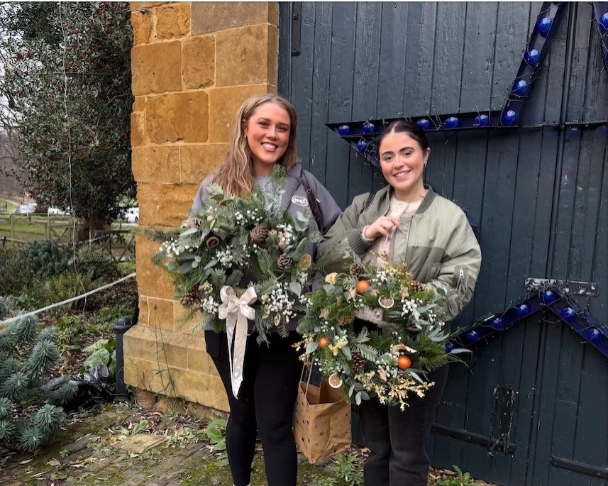 Two students showing their Christmas Wreaths after their florry Wreath Making